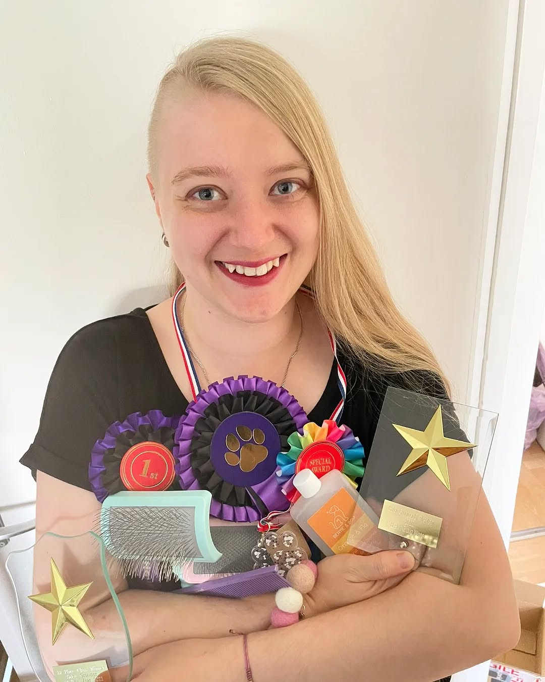 Jazz Ames holding her grooming competition rosettes and trophies